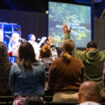 Congregation worships with hands raised at Desert Vineyard Church in Lancaster, CA.
