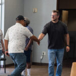 Two men greet each other with a handshake at Desert Vineyard Church in Lancaster, CA.